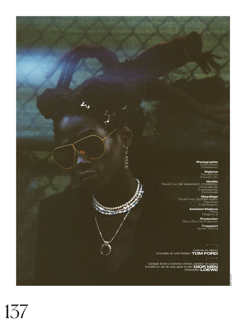 Portrait of a Black woman with aviator sunglasses, necklaces, and braided hair against a green background with text elements on the right.