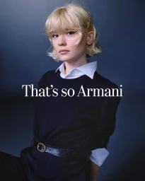 Portrait of a blonde woman wearing a black sweater with a white collar against a dark grey background