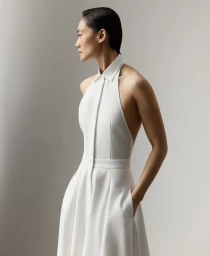Model in a halter-neck white dress with a collared neckline against a clean white backdrop