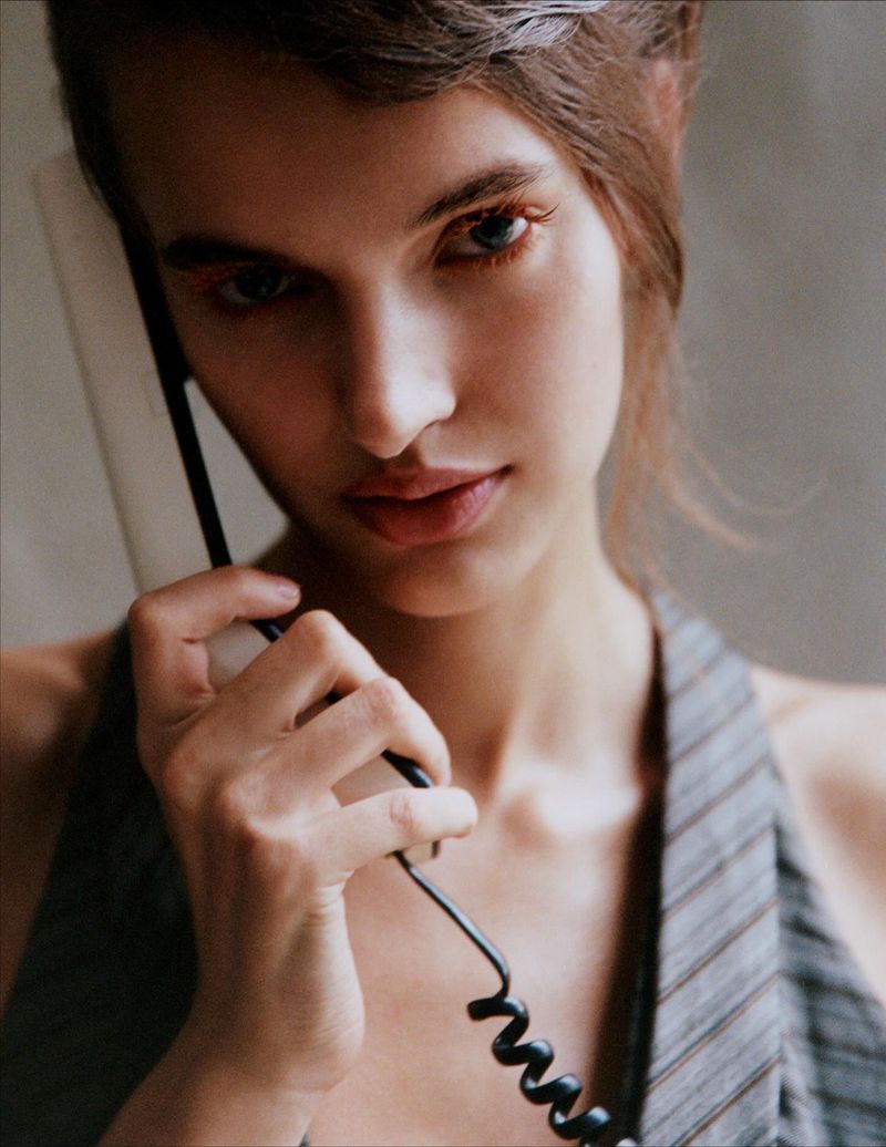 Close-up portrait of a woman holding a telephone receiver to her ear, showcasing a contemporary fashion and beauty aesthetic.