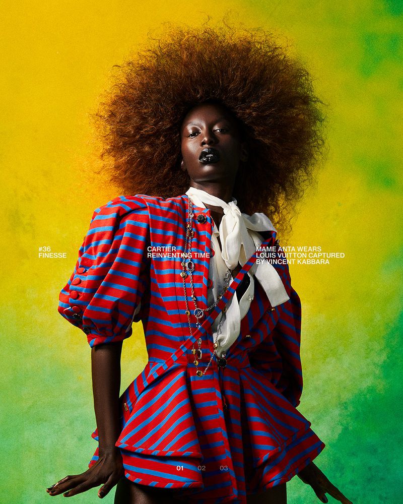 Fashion editorial featuring a Black model with large afro wearing a red and blue striped jacket, against a vibrant yellow and green backdrop.
