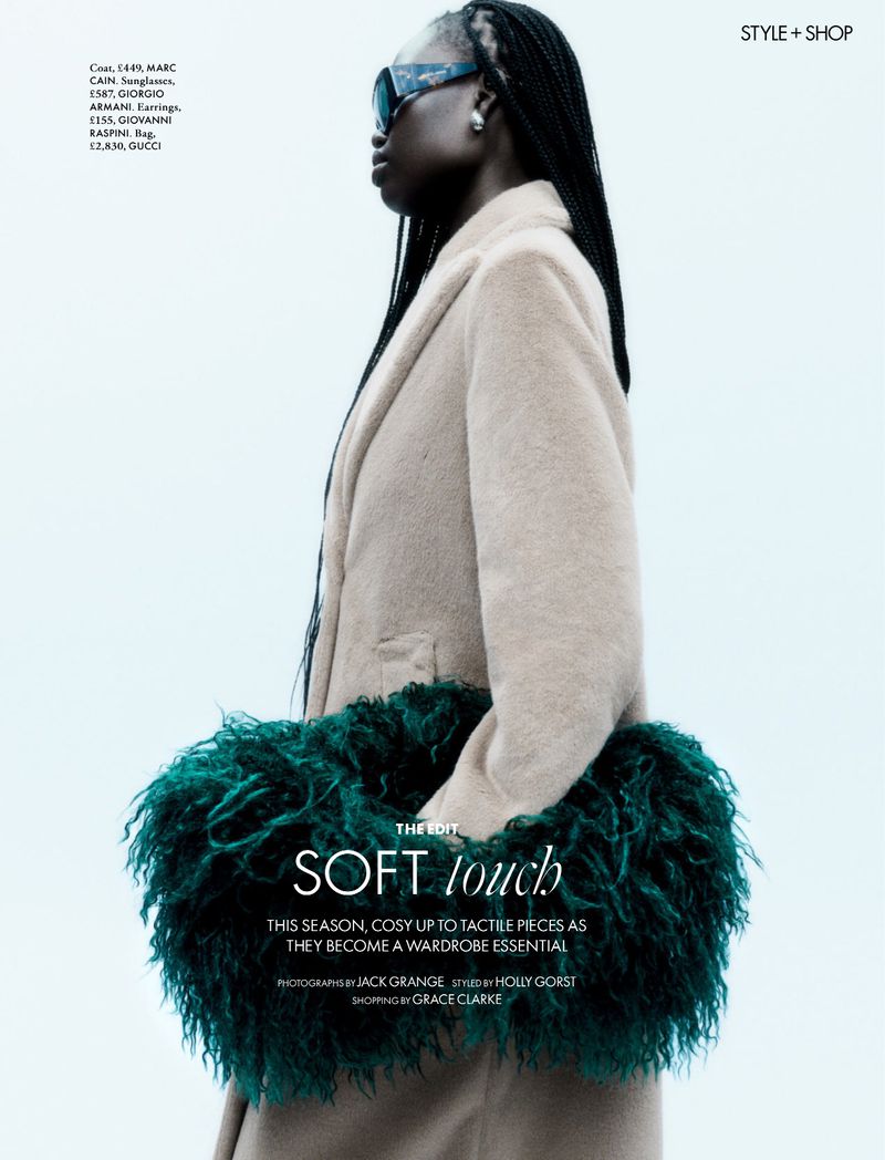 Adual Akol in a beige coat holding a green fluffy bag against a white seamless background for Elle UK.