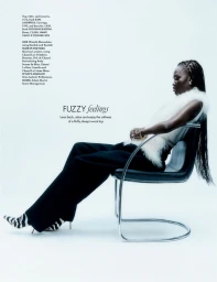 Model Adual Akol seated in a chrome and black leather chair against a white seamless background for Elle UK.