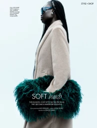 Adual Akol in a beige coat holding a green fluffy bag against a white seamless background for Elle UK.