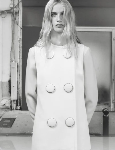 Model Lauren Huyskens wearing a light double-breasted buttoned coat outdoors in a black and white editorial portrait.