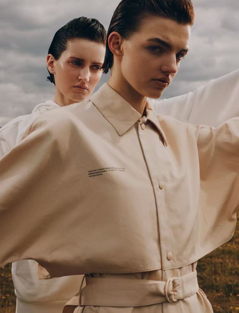 Two models with wet-look hair posing outdoors against an overcast sky for 10 Magazine