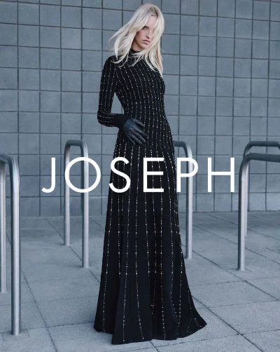 Model Vilma Friedlander poses in a long embellished black dress and leather gloves in front of a tiled wall for Joseph.
