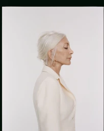 Profile portrait of an elderly woman with white hair wearing a light-coloured blazer against a plain white background