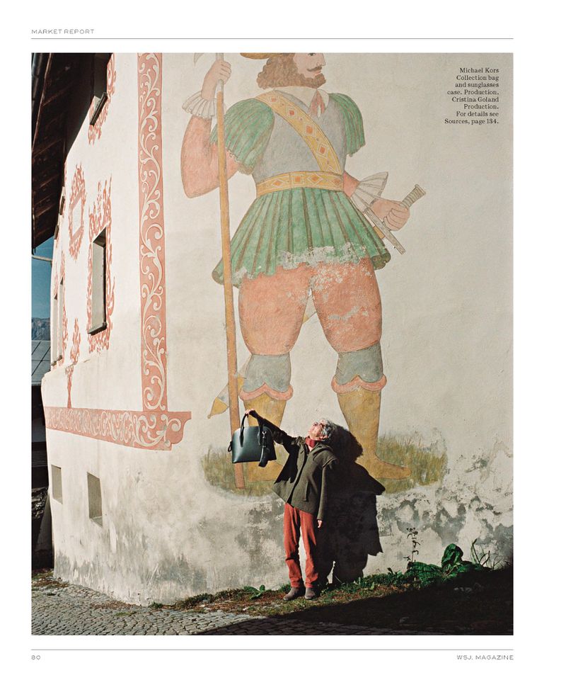 Adult woman showcases a handbag in front of a building mural featuring a Renaissance-era figure with a spear and vintage attire.
