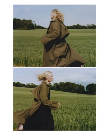 Woman in trench coat runs through wheat field on sunny day. Fashion editorial shot of blonde adult female in rural environment.
