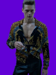 Model Caesar van den Idsert wearing an open baroque print shirt and black leather pants against a solid purple studio backdrop.