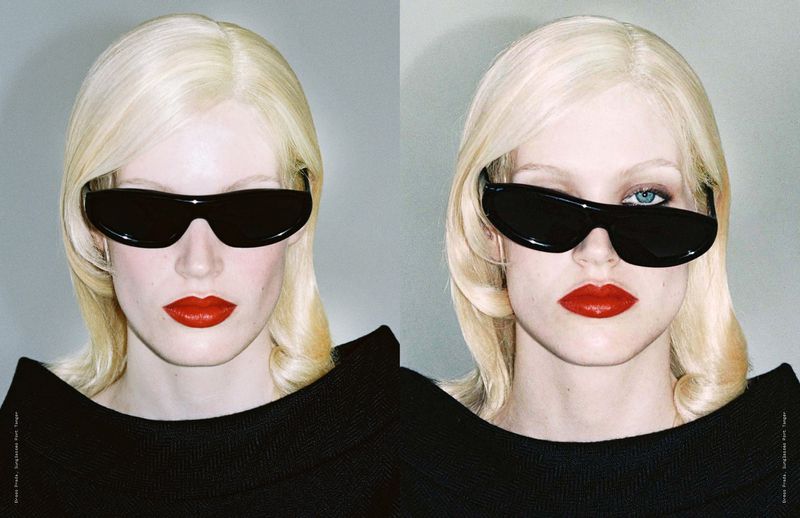 Two women with blonde hair and red lipstick pose in sunglasses in a studio with a light gray background, showcasing a minimalist fashion style.