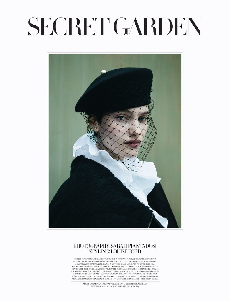 Elegant fashion portrait of a woman in a black beret and net veil, wearing a white ruffled collar, posing against a muted green background.