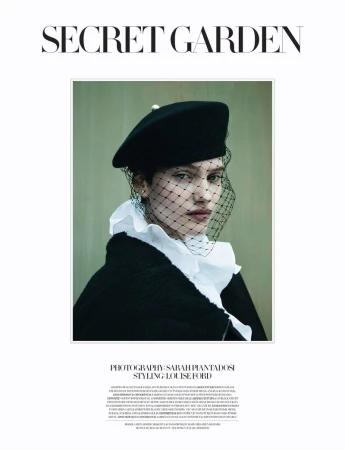 Elegant fashion portrait of a woman in a black beret and net veil, wearing a white ruffled collar, posing against a muted green background.