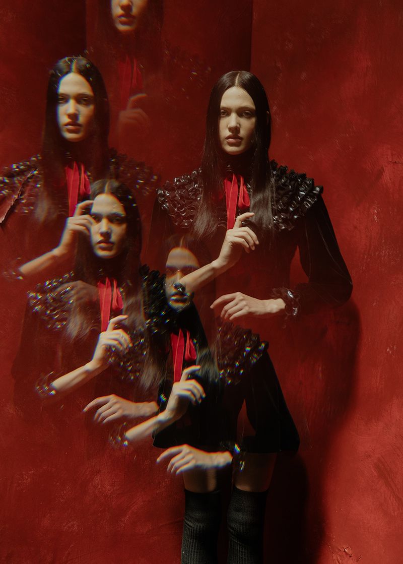 Multiple exposures of a young woman with long brown hair, wearing a black dress and red scarf, stand in a red room. Fashion photography.