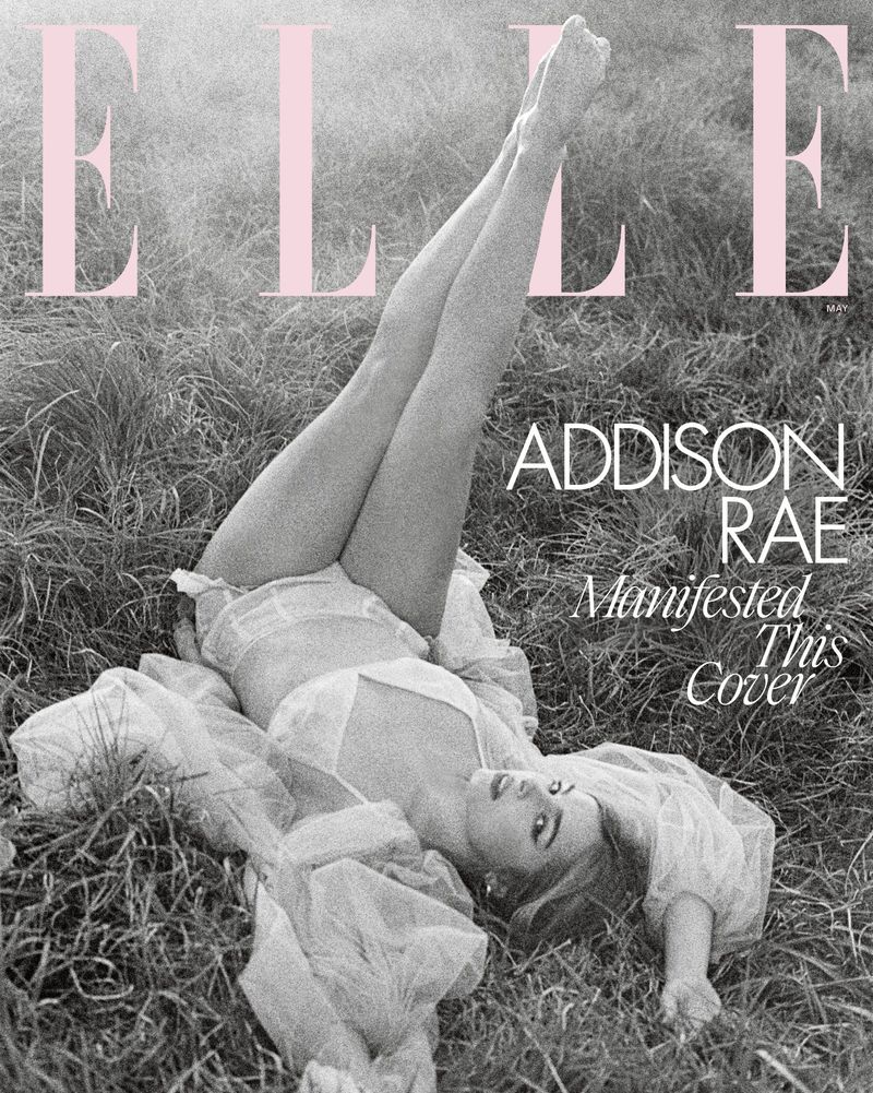 Addison Rae lying in grass, legs raised for Elle magazine cover, wearing sheer white clothing. Monochromatic image with pink magazine logo.