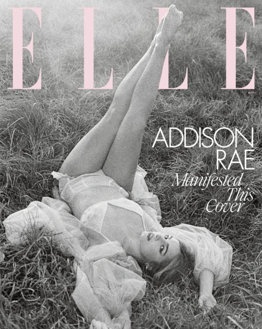 Addison Rae lying in grass, legs raised for Elle magazine cover, wearing sheer white clothing. Monochromatic image with pink magazine logo.