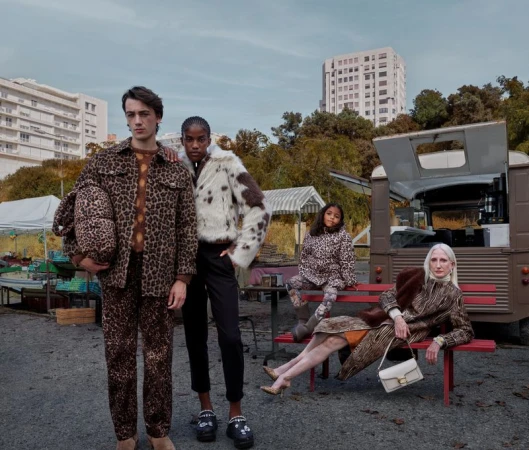 Fashion shoot featuring five models in a gritty urban setting wearing animal print outfits and faux fur coats against a backdrop of a food truck.