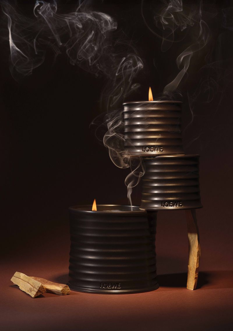 Stacked Loewe candles burning with smoke, presented in a warm, inviting studio setting, suggesting relaxation and ambiance creation.