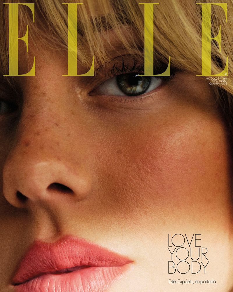 Close-up of a woman's face on the cover of Elle magazine, featuring visible freckles, blonde hair, and pink lipstick.