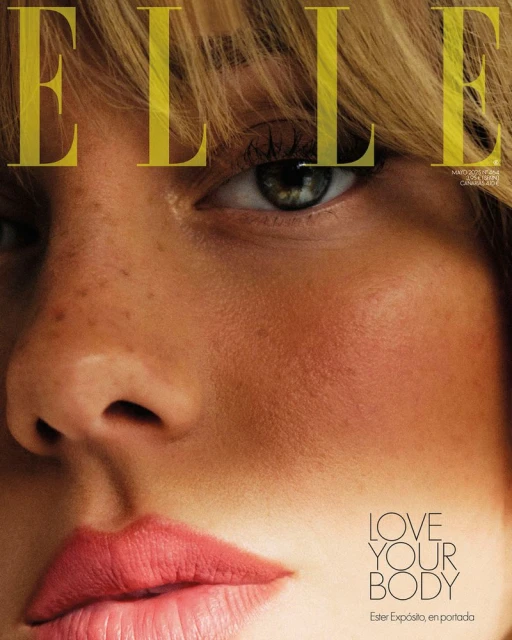 Close-up of a woman's face on the cover of Elle magazine, featuring visible freckles, blonde hair, and pink lipstick.