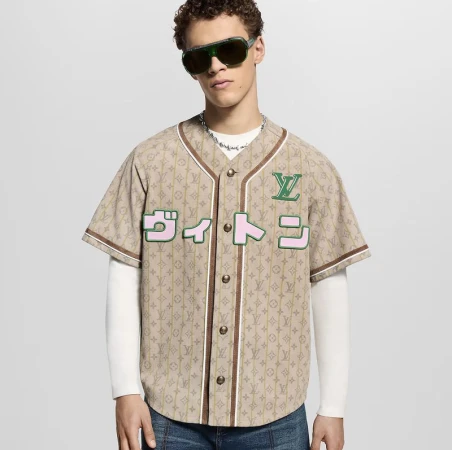 A stylish adult male poses indoors wearing a Louis Vuitton baseball jersey, jeans, and sunglasses, showcasing a modern fashion look.