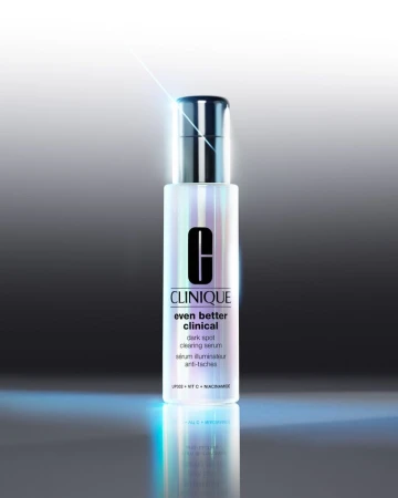 Clinique Even Better Clinical dark spot clearing serum stands against a gradated gray background with a reflective surface.
