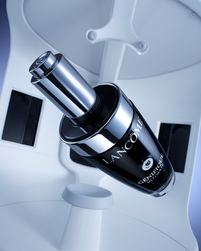 Lancome Genifique Ultimate skin serum bottle in a modern beauty display with black, silver, and white tones in a studio setting.