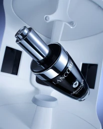 Lancome Genifique skincare bottle floating upright against a sleek white modular studio background with blue lighting.