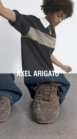 Model with curly hair wearing a colorblocked polo shirt and brown sneakers for Axel Arigato A/W25.
