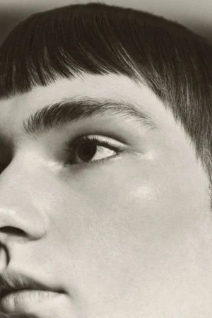 Close-up portrait of a person with dark blunt-cut bangs and natural skin texture shot for Schon Magazine