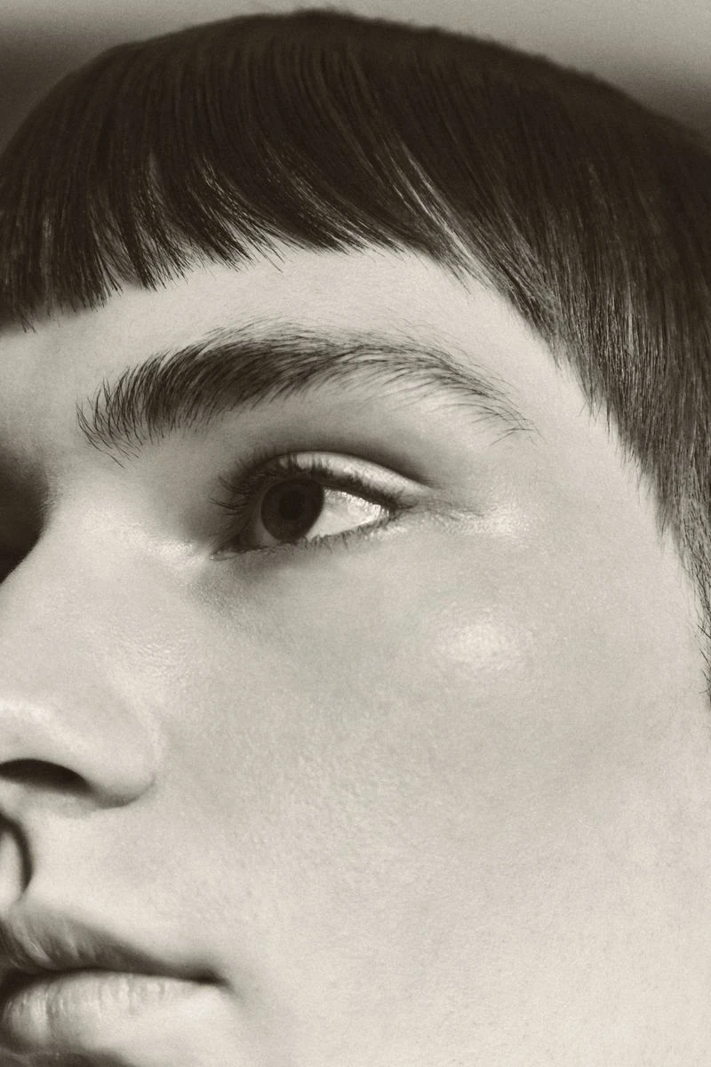 Close-up portrait of a person with dark blunt-cut bangs and natural skin texture shot for Schon Magazine