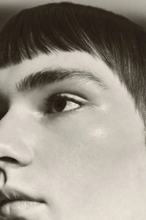 Close-up portrait of a person with dark blunt-cut bangs and natural skin texture shot for Schon Magazine