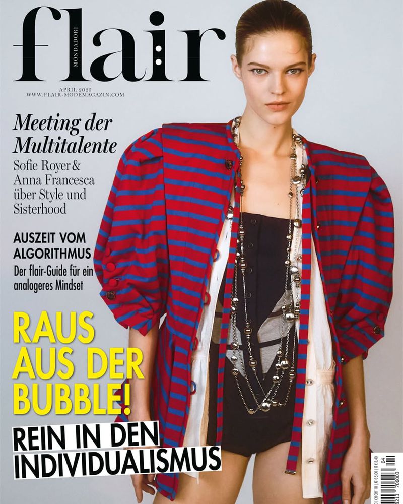 Fashion magazine cover featuring a model wearing a striped jacket and jewelry, with magazine text and branding visible on the cover.