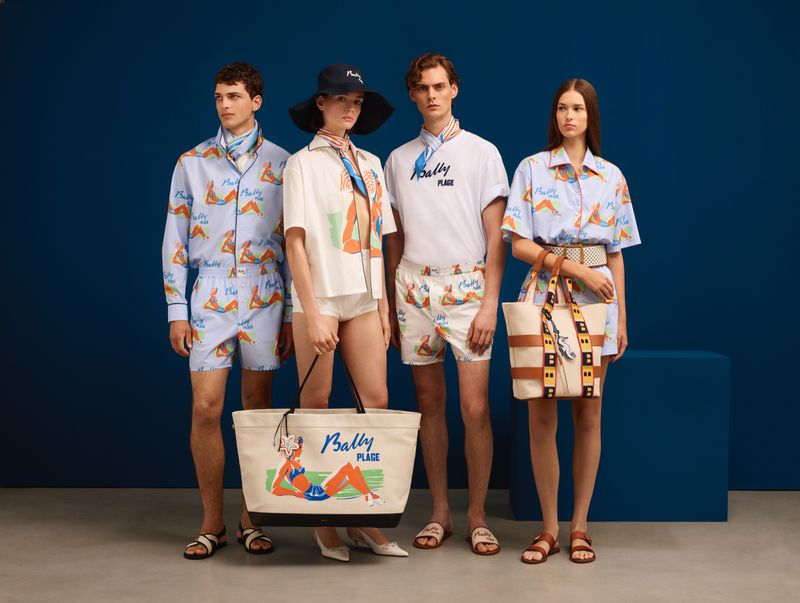 Four fashion models pose against a blue wall wearing Bally Plage themed beach attire including shirts, shorts, totes, and sandals.