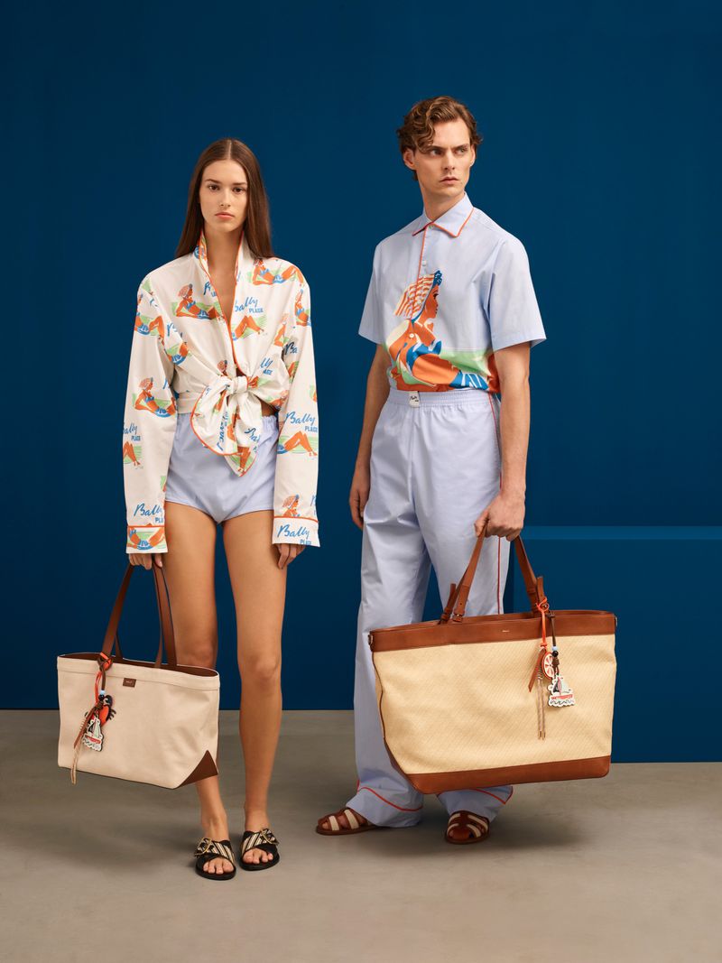 Two fashion models showcase beach-themed apparel and tote bags against a deep blue studio backdrop, creating a bright and summery aesthetic.