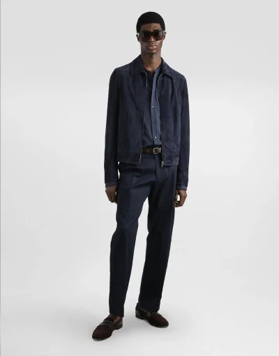 Model Zaram Obasi in dark sunglasses and a navy suede jacket standing against a white backdrop for Dolce & Gabbana