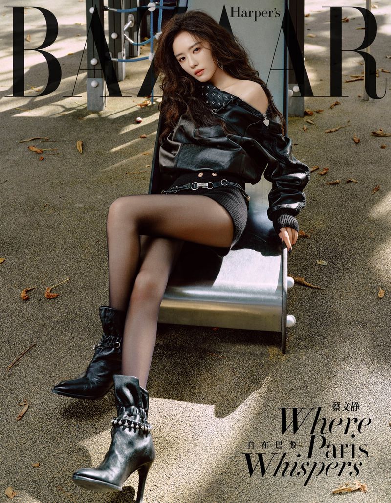 Harper's Bazaar magazine cover featuring an Asian female model with long dark hair sitting on a playground slide wearing a black jacket and boots.
