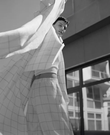 Model Saskia de Brauw in a checkered coat and trousers looking up in a black and white editorial shot for Dusan.