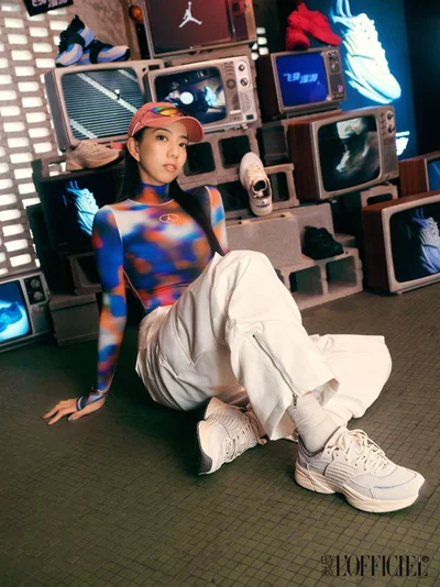 Woman in pink cap and multicolored top sitting amidst stacked vintage televisions for Jordan