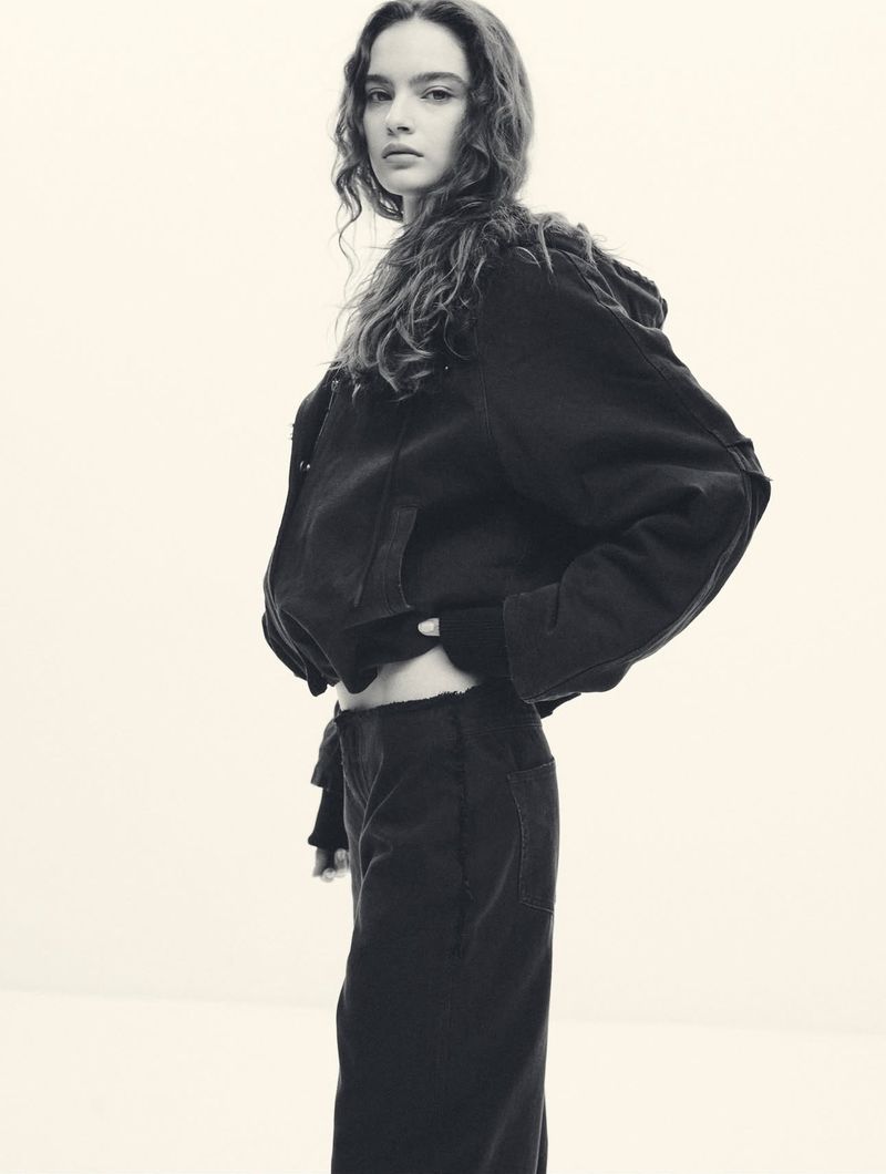 Model Vira Boshkova in dark outerwear wearing a black jacket against a plain white background for the Khy x Canvas campaign