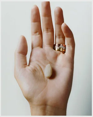 Close-up of an open hand holding a small pale almond resting against a light background