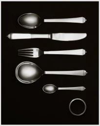 Top-down view of Georg Jensen silver cutlery and a napkin ring arranged on a dark background for a holiday campaign.