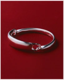 Silver bangle bracelet resting on a rich red fabric surface for the Georg Jensen Holidays Campaign.