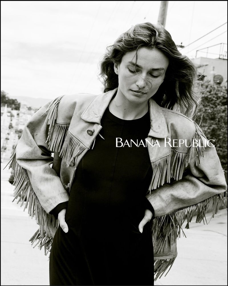 Black and white portrait of a woman wearing a fringed jacket in an urban setting, featuring the Banana Republic logo.