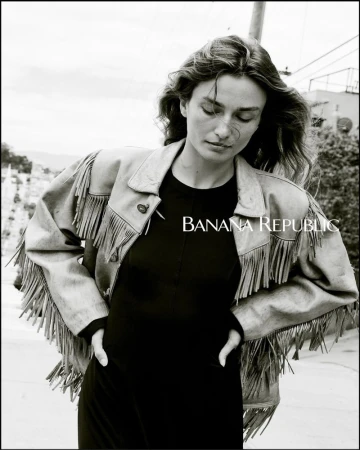 Black and white portrait of a woman wearing a fringed jacket in an urban setting, featuring the Banana Republic logo.