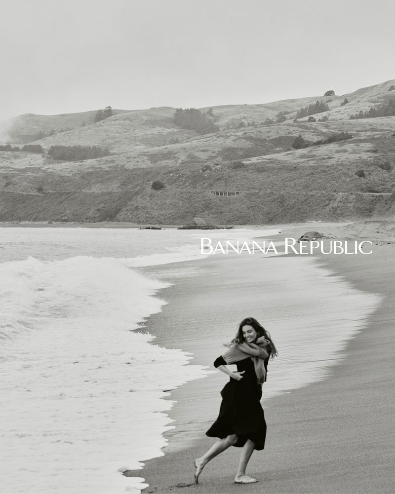 A monochrome fashion shot features a woman in a dress running barefoot on a beach near the ocean, with Banana Republic logo text overlay.
