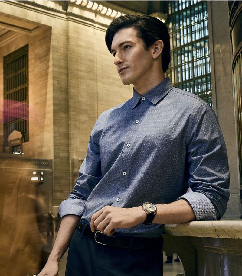 Man in button-down shirt in Grand Central Terminal. He leans on a marble ledge and looks toward light in the famous NYC train station.
