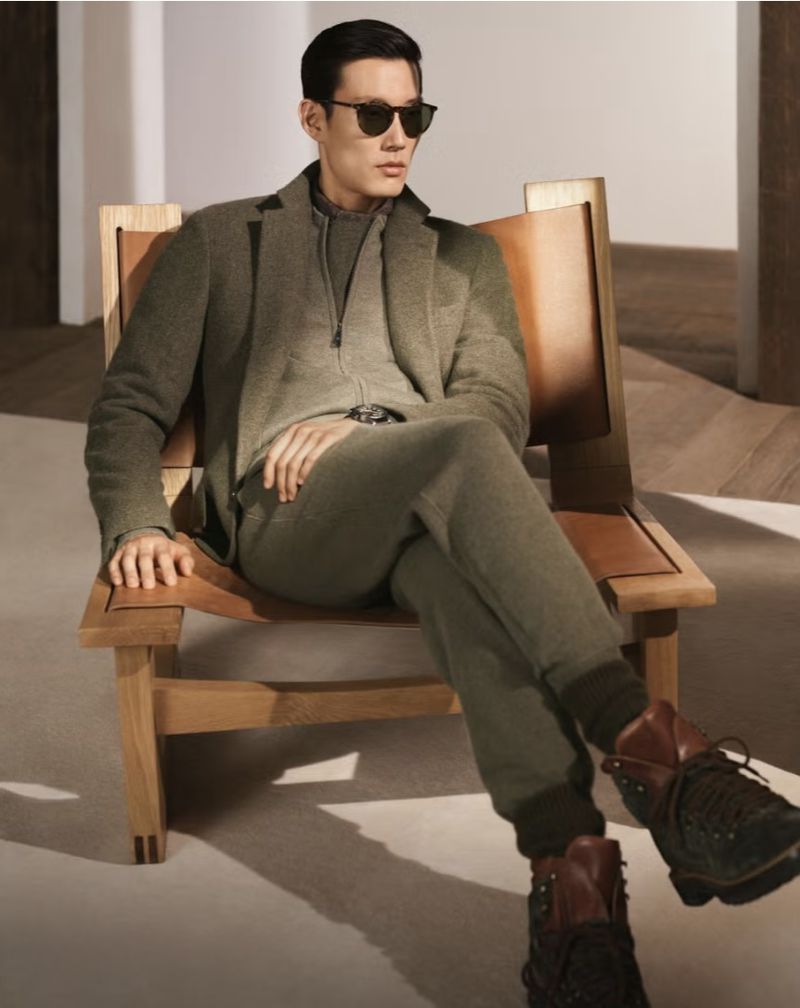 Man wearing a green suit and sunglasses seated in a wooden leather chair for the Ralph Lauren Purple Label fall campaign