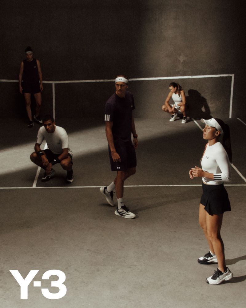 Group of young adult athletes in athletic wear in a dimly lit court, showcasing an active lifestyle scene with Y-3 logo branding.